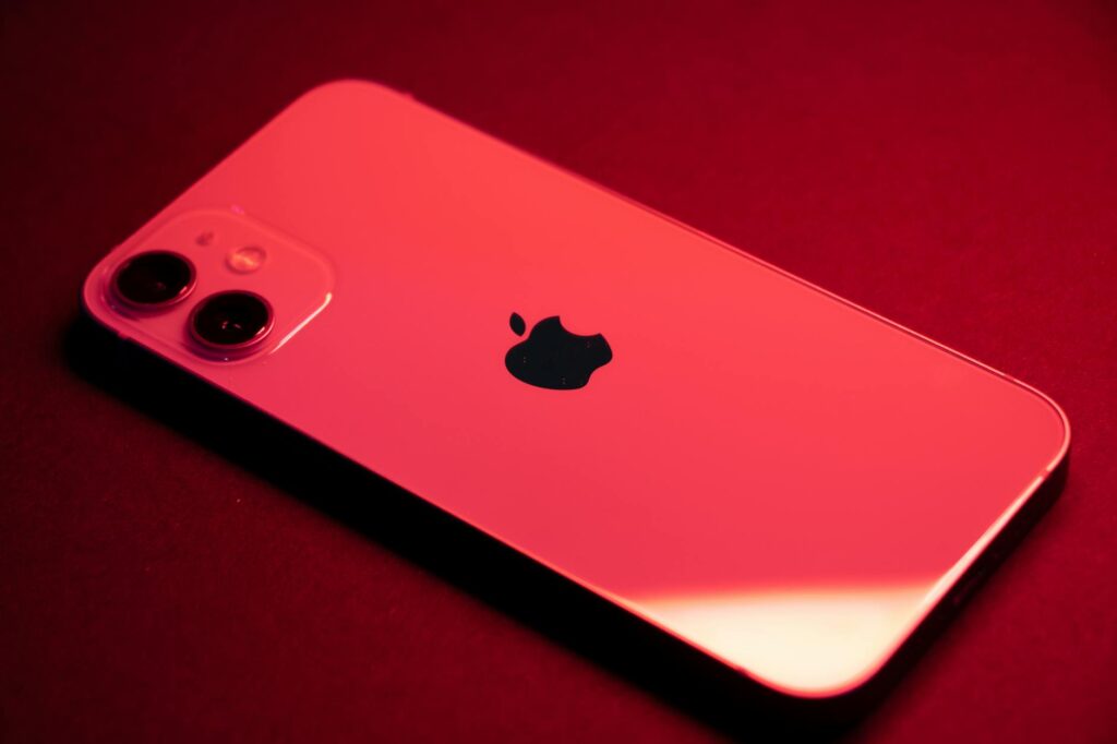 Close-up of a red smartphone with dual lenses on a red backdrop, highlighting sleek design and te... (Photo by Tessa Charles on Pexels)