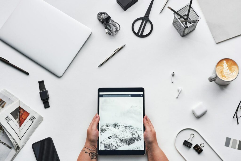 Flat lay of a modern workspace featuring a tablet, gadgets, and coffee for creative work. (Photo by fauxels on Pexels)