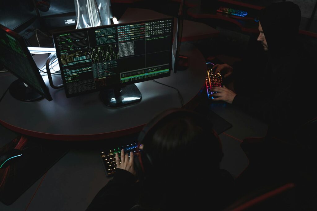 A group of people in a dark room working on computers, related to cybersecurity. (Photo by Tima Miroshnichenko on Pexels)