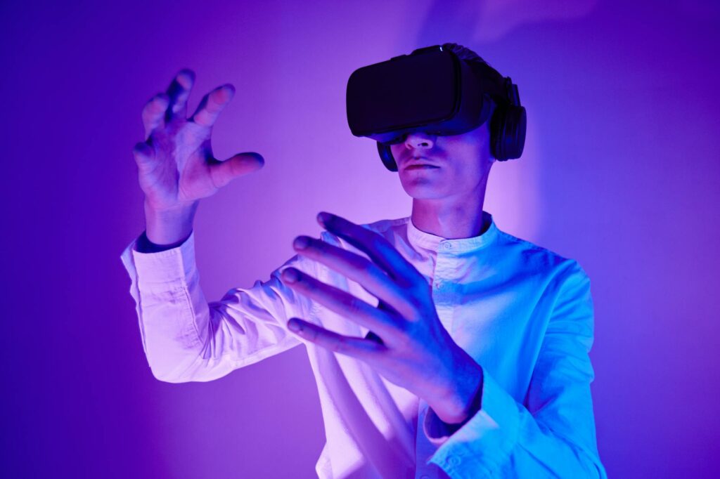 A man wearing VR goggles interacts with a virtual environment in a studio shot with vibrant light... (Photo by Michelangelo Buonarroti on Pexels)