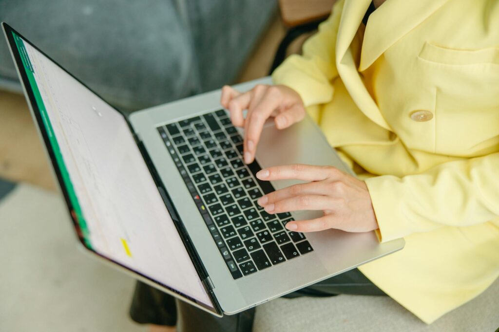 A person in a yellow jacket typing on a laptop indoors. Perfect for depicting work from home or b... (Photo by Yaroslav Shuraev on Pexels)