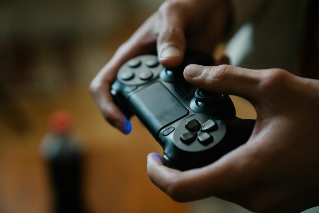 Crop anonymous male pressing buttons on console controller while playing video game in house on b... (Photo by Eren Li on Pexels)
