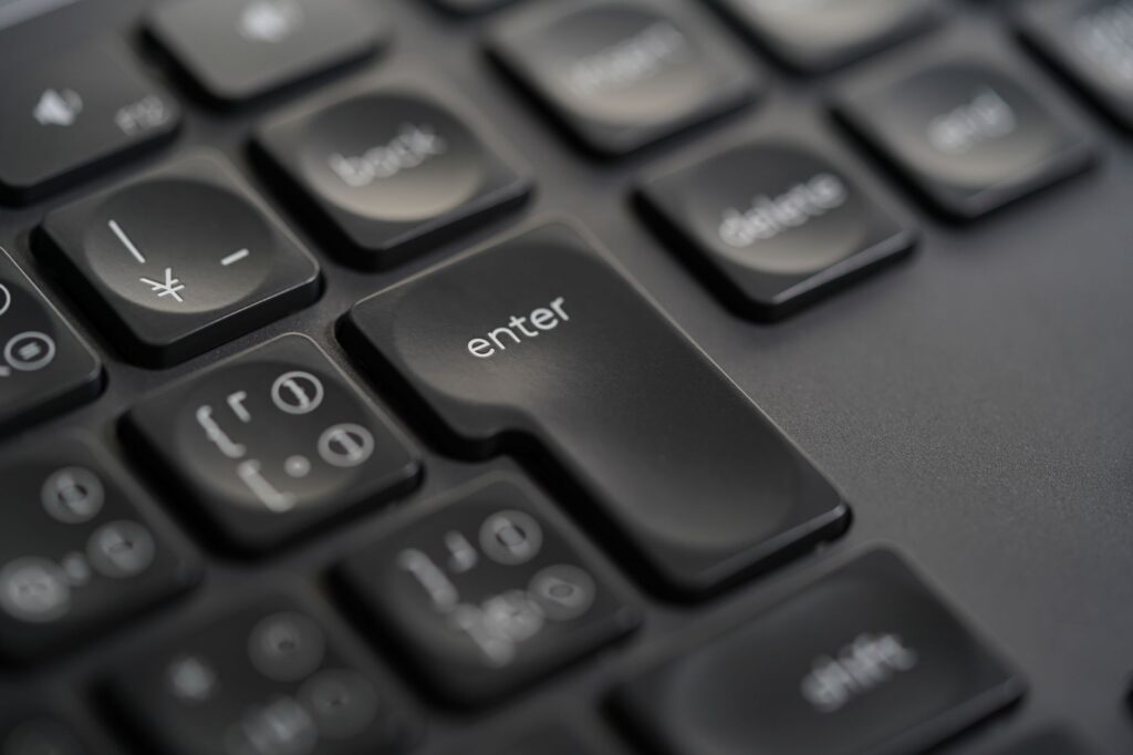 Detailed close-up photograph of a black keyboard's enter key, showing precision and modern design. (Photo by Unseop Kang on Pexels)